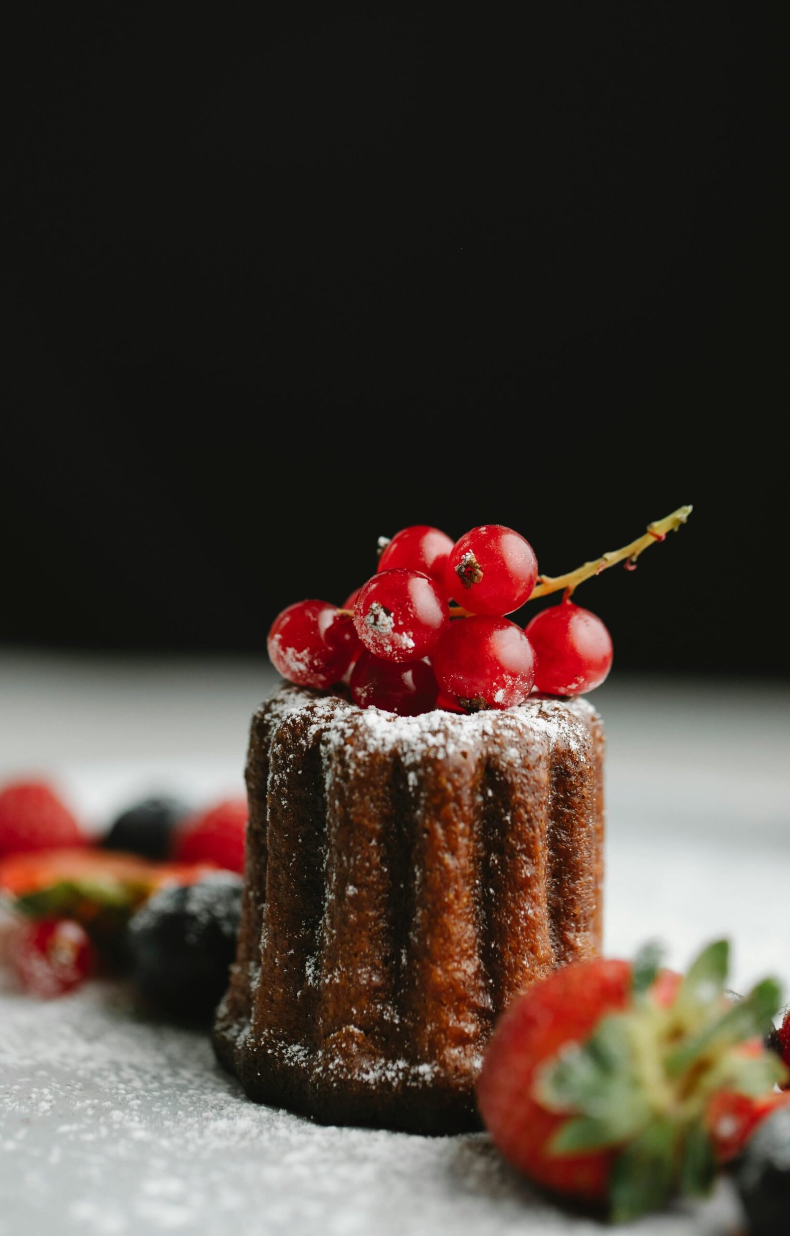 Chocolate cake topped with berries and powdered sugar on a black background. Captivating dessert shot.